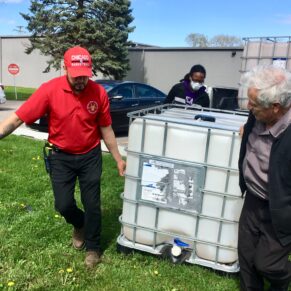 Image of people caring water tank outside of the pantry.